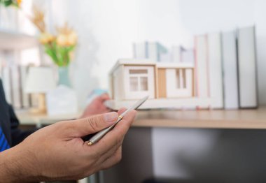 Bir emlakçı, bir müşteriye model bir evin özelliklerini açıklar. Çağdaş bir ofis ortamında anlayışı teşvik eder..