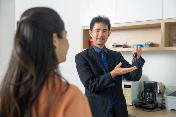 A real estate agent presents keys to a client, symbolizing the completion of a home purchase and new beginnings.
