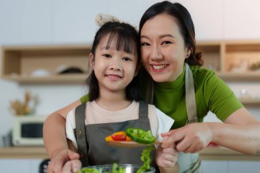 Bir anne ve kızı, modern bir mutfakta taze sebzelerle sağlıklı yemekler hazırlarken harika bir yemek deneyimi paylaşıyor..