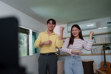 Canlı bir çift dans ediyor ve bir video görüşmesinde eğleniyor, neşeli bir ev ortamında neşe ve bağlantı sergiliyorlar..