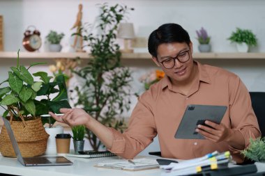 Modern iletişim ve üretkenlikte teknolojinin rolünü vurgulayan şık bir ofiste tabletle ilgilenen bir adam..