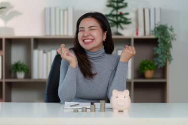 Bir kadın elinde bozuk para tutarken gülümseyerek birikimleri ve finansal başarıları hakkında sevinçlerini dile getirir..