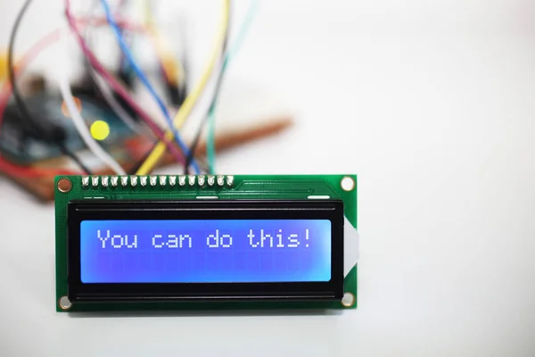 Pozitif onayı gösteren mavi bir LCD ekranı 'Bunu yapabilirsin!' Arka plandaki bir bilgisayar devre kartından kablolar geliyor. Bunu yapabilirsin.