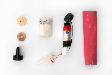 Atılmış tek kullanımlık elektronik sigara tüpünün bileşenleri beyaz bir yüzeye serilmiş, pil, kabuk, ağızlık ve vape sıvısı parçalarını göstermektedir.. 