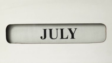 Temmuz 'dan Ağustos' a bir retro ofis takvimi kaydırıldığı görülüyor. Ayın metni siyah renkli ve beyaz bir tuval üzerine basılmış..