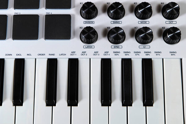 Close up of a midi keyboard with pads and knobs.