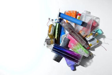 A collection of broken discarded electronic cigarette vapes that have been collected from roadsides. Shot on a white worktop.