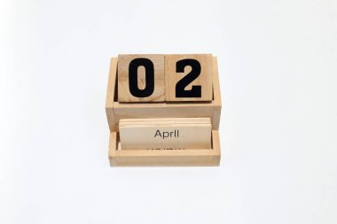 2 Nisan 'ı gösteren daimi ahşap takvimi kapat. Yakın çekim, beyaz bir arkaplanda izole edilmiş.