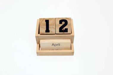 12 Nisan 'ı gösteren daimi ahşap takvimi kapat. Yakın çekim, beyaz bir arkaplanda izole edilmiş.