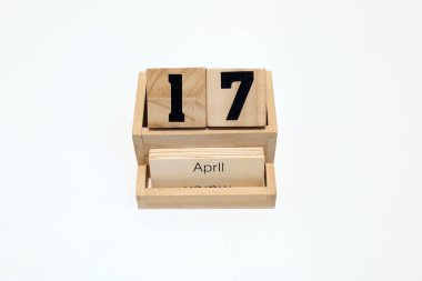 17 Nisan 'ı gösteren daimi ahşap takvimin kapağını kapatın. Yakın çekim, beyaz bir arkaplanda izole edilmiş.