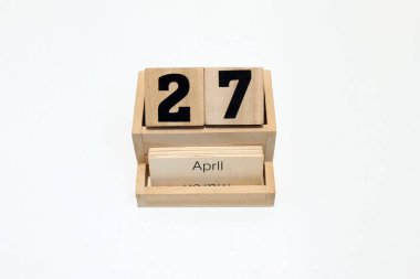 27 Nisan 'ı gösteren ahşap daimi takvimi kapat. Yakın çekim, beyaz bir arkaplanda izole edilmiş.
