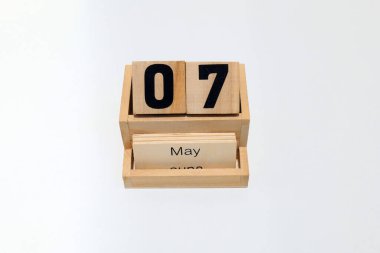 7 Mayıs 'ı gösteren daimi ahşap takvimin kapağını kapatın. Yakın çekim, beyaz bir arkaplanda izole edilmiş.