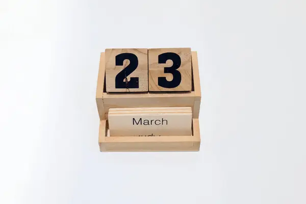 23 Mart 'ı gösteren ahşap daimi takvimi kapat. Yakın çekim, beyaz bir arkaplanda izole edilmiş.