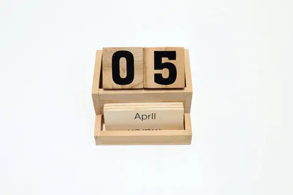 5 Nisan 'ı gösteren daimi ahşap takvimi kapat. Yakın çekim, beyaz bir arkaplanda izole edilmiş.