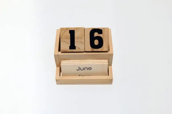 16 Haziran 'ı gösteren daimi ahşap takvimi kapat. Yakın çekim, beyaz bir arkaplanda izole edilmiş.