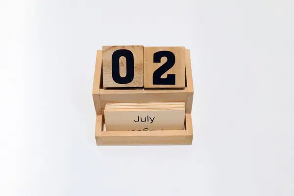 2 Temmuz 'u gösteren ahşap daimi takvimi kapat. Yakın çekim, beyaz bir arkaplanda izole edilmiş.