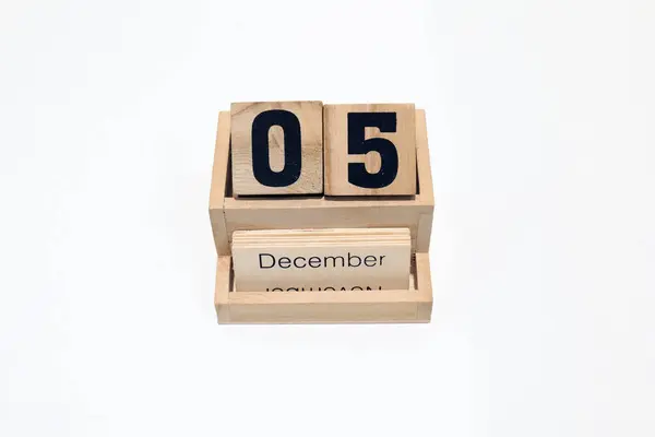5 Aralık 'ı gösteren daimi ahşap takvimi kapat. Yakın çekim, beyaz bir arkaplanda izole edilmiş. 