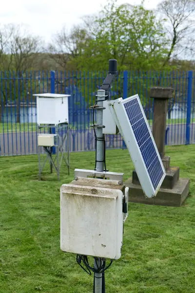 stock image Weather recording equipment setup outside. A solar panel can be seen, and a whte stevenson screen is blurred in the background.