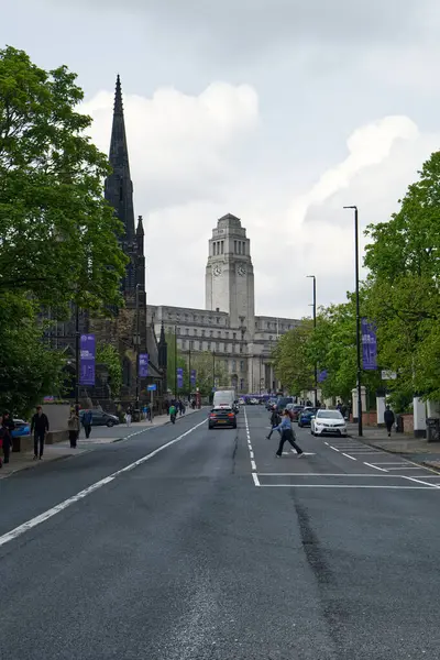 Leeds, UK 05 08 2024 Leeds Üniversitesi Parkinson Binası saat kulesine doğru meşgul bir Blenhiem Terrace 'a bakıyor. Yaya geçitleri yolda yürüyor, arabalar ve bisikletçiler de etrafta.