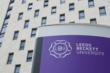 Leeds, UK 05 08 2024 Leeds Beckett Üniversitesi tabelasında gül amblemi var. Modern bir konut bloğu bulanık bir şekilde görülebilir..