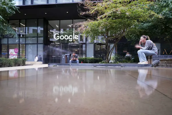 Londra, UK 08 27 2024 Google Kings Cross yakınlarındaki Londra 'da. İnsanlar dışarıda suyun yanında oturur, telefonlara bakar ya da mesaj gönderirler. Uzun gündüz maruz kalma