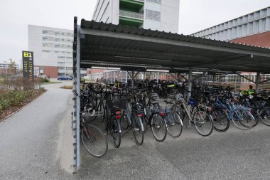 Aarhus, Danimarka 108 2024 Aarhus Üniversitesi Hastanesi 'nin kapalı bir bisiklet park alanı bisikletlerle doludur. Metal çatı nemli havada her şeyi kuru tutar..