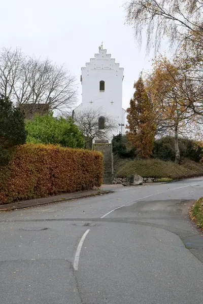 Aarhus, Danimarka 108 2024 Beyazboyanmış Skejby köyü kilisesinin yanından geçen bir yol var.