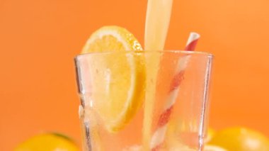 Turuncu arka planda portakal suyu bardağı