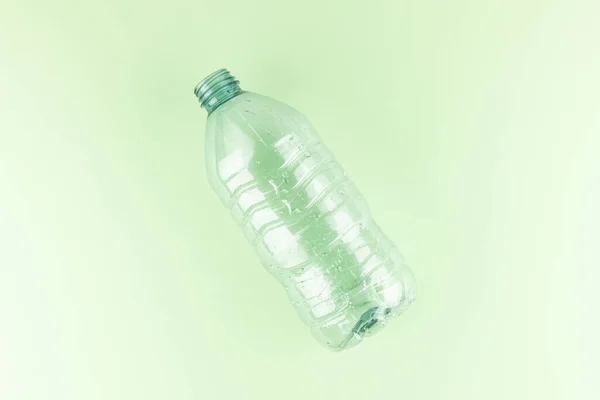 Minimalist boş bir plastik şişe. Pastel açık yeşil arka plan, düz yatak, stüdyo çekimi.