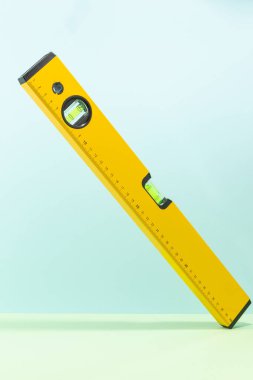 Yellow spirit level isolated on cyan and green background clipart