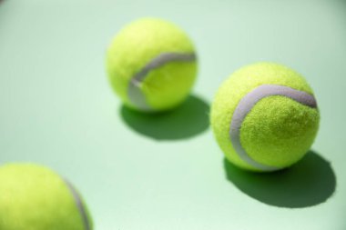 Açık yeşil arka planda, zıt gölgeli 3 tenis topu