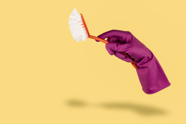 Hand in color cleaning glove isolated on yellow