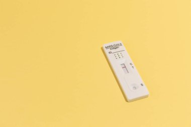 Sarı renk üzerinde Covid-19 için hızlı test kiti aygıtının resmini kapat