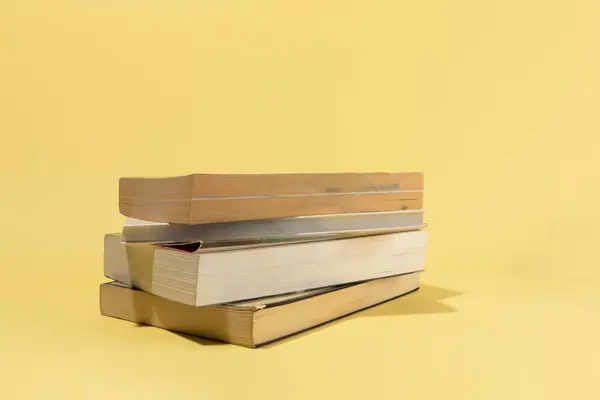 Bir beyin, bir ampul ve sarı arka plan üzerine kitaplar.