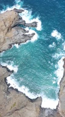 Gökyüzü manzaralı dalgalar uzak kayalıklarda kırılıyor.