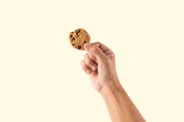 Erkek el pastel sarı arka planda izole edilmiş bir kurabiye tutuyor. Yüksek kalite fotoğraf