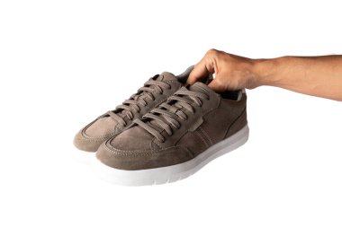 Erkek el, arka planda izole edilmiş kahverengi bir çift ayakkabı tutuyor. Yüksek kalite fotoğraf