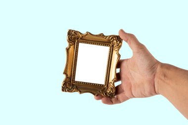 Cyan arka planda izole edilmiş altın rengi bir mini çerçeveyi tutan erkek el. Yüksek kalite fotoğraf