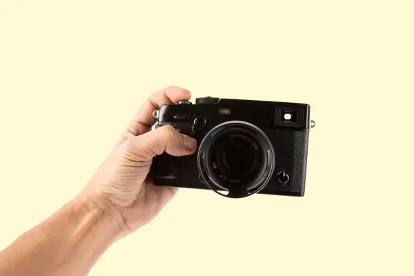 Erkek el, sarı arkaplanda izole edilmiş dijital bir fotoğraf makinesi tutuyor. Yüksek kalite fotoğraf