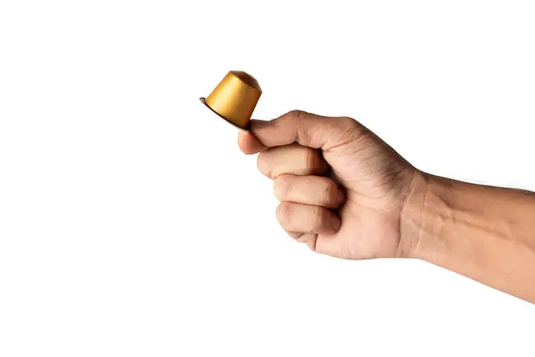 Beyaz arka planda izole edilmiş altın bir kahve kapsülü tutan erkek el. Yüksek kalite fotoğraf