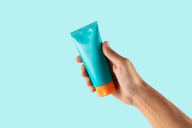 Cyan arka planda el ele tutuşan güneş kremi. Yüksek kalite fotoğraf