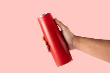 Erkek el pembe arka planda kırmızı bir şampuan şişesi tutuyor. Yüksek kalite fotoğraf