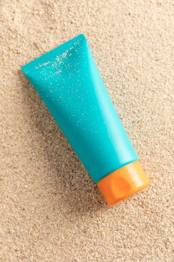 Kum arka planında izole edilmiş Cyan güneş kremi kremi şişesi. Yüksek kalite fotoğraf