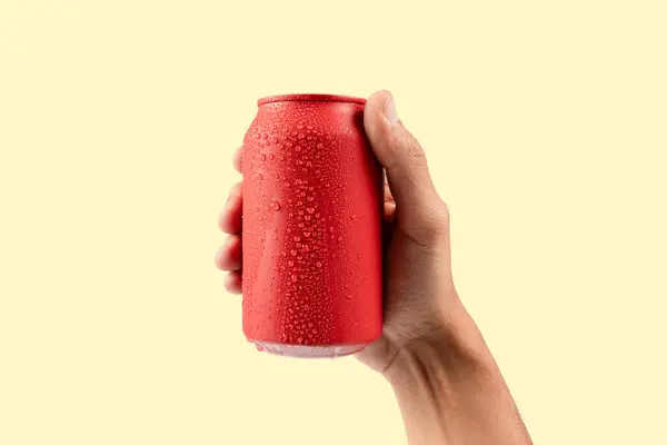 Kırmızı alüminyum içen erkek el, sarı arka planda izole edilmiş gazoz kutusu modeli. Yüksek kalite fotoğraf