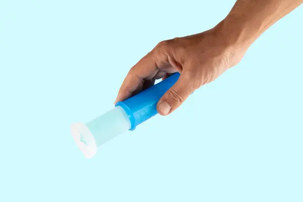 Cyan arka planda izole edilmiş erkek tuvalet deodorantını tutuyor. Yüksek kalite fotoğraf