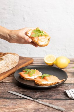 Elle tutulan füme somon tostu roka ile servis edilir, sağlıklı kahvaltı. Yüksek kalite fotoğraf