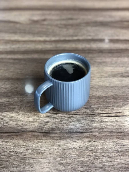 stock image Blue cup with black coffee and wood grain table