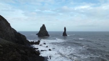 Reynisfjara 'da okyanusta iki kaya, Vik' in (Güney İzlanda) yanında siyah bir kumsal. Drone 'la çekilmiş. Portföyümde farklı pozlar var..