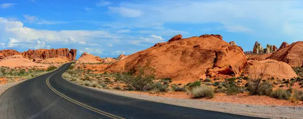 沙漠中的孤寂 孤独驾驶在漆黑的黑色道路 红色岩石和雄伟的山脉上 — 图库照片
