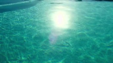 Parlayan Oasis: Saf Mavi Yüzme Havuzu Suyuna Yansıyan Güneş Işığının 4K Videosu